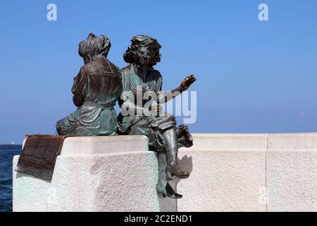 Bronze statue of two ladies on the seafront promenade in Trieste, Italy. Stock Photo