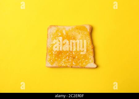 Toast with orange jam on yellow background, close up Stock Photo