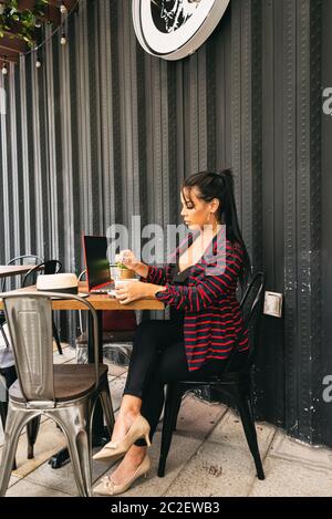 woman working on a bar terrace, having a coffee, enterprising woman Stock Photo