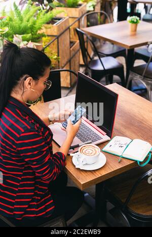 woman on the terrace checking her phone and planning her schedule Stock Photo