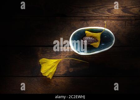 Pine cone in a tiny bowl on an old grungy wooden plnak background Stock Photo