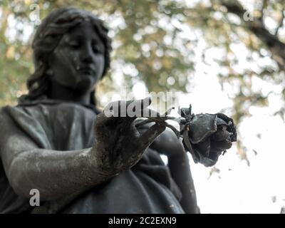 an angel in a graveyard holds a farewell rose in his hand Stock Photo