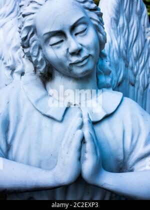 an angel with praying hands in a cemetery. symbol for guardian angel or peace angel Stock Photo