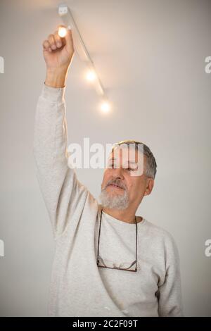 Senior man installing a ceiling light n a freshly renovated appartment Stock Photo