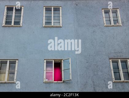 a desolate facade in an old apartment building. window with a red curtain Stock Photo