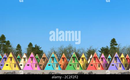 Many colorful wooden guest houses stand in a row against a forest and clear sky. A chalet or summer wellness camp with colorful cottages in the shape Stock Photo