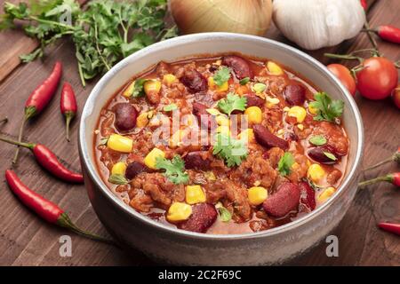 Chili con carne, a traditional Mexican dish with red beans, cilantro leaves, ground meat, and chili peppers, a closeup with ingr Stock Photo