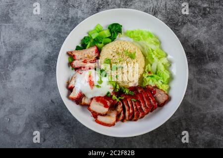 Barbecued red pork and crispy pork in red sauce, served with rice and vegetable on white plate. Stock Photo