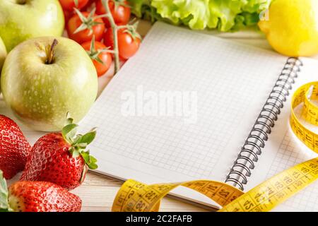 Fresh organic vegetables and fruits, open blank notebook and pen on wooden background. Healthy food and healthy life concept. Stock Photo