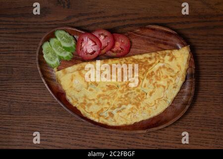 Top view of plain egg omelette with tomato and cucumber isolated on wooden background Stock Photo