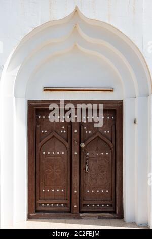 Traditional dark brown wooden door in town of Al Ayjah near Sur, Oman, under arched entrance Stock Photo