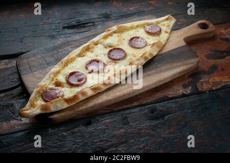 Turkish pide with sausage isolated on rustic wooden table