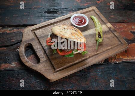 Turkish Kofte Ekmek. Meatball Sandwich with tomatoes, onion and green pepper isolated on rustic wooden background Stock Photo