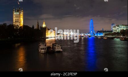 London, England, UK - November 9, 2012: The Palace of Westminster and London Eye are lit up at night on the banks of the River Thames in central Londo Stock Photo