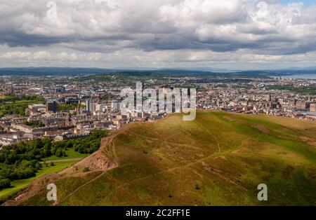 The cityscape of Edinburgh is laid out below Arthur's Seat and Salisbury Crags in Holyrood Park. Stock Photo