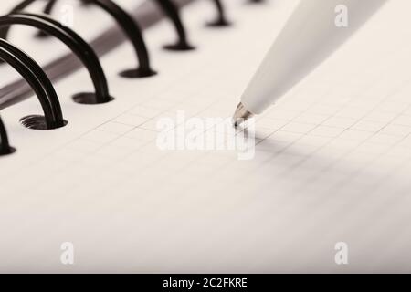 Opened notepad in a cage with an automatic plastic ballpoint pen close-up. Stock Photo