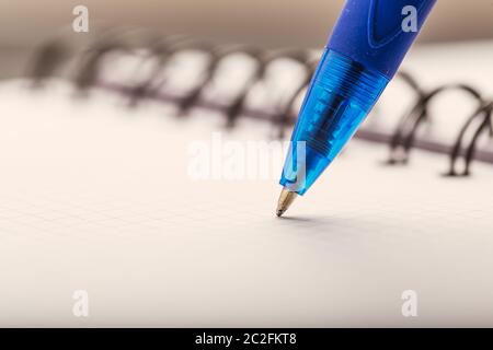 Opened notepad in a cage with an automatic plastic ballpoint pen close-up. Stock Photo