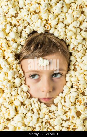 Creative portrait of a boy with his face surrounded by popcorn. Stock Photo