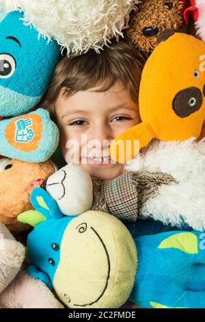 Creative portrait of a boy with his face surrounded by stuffed animals. Stock Photo