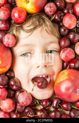 Creative portrait of a boy with his face surrounded by fruits. Stock Photo