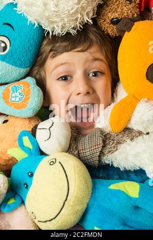 Creative portrait of a boy with his face surrounded by stuffed animals. Stock Photo