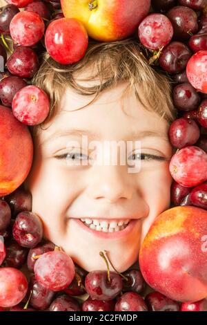 Creative portrait of a boy with his face surrounded by fruits. Stock Photo