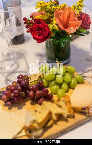 Food, cheese and fruit on table with beautiful flower arrangement Stock Photo