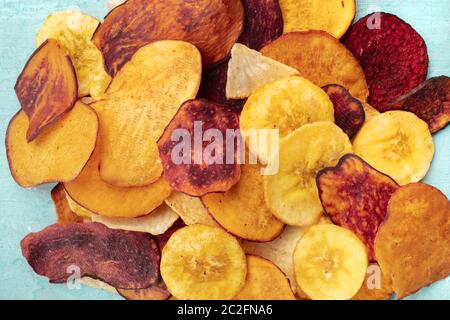 Dry fruit and vegetable chips, healthy vegan snack, a mixed heap on a blue background Stock Photo