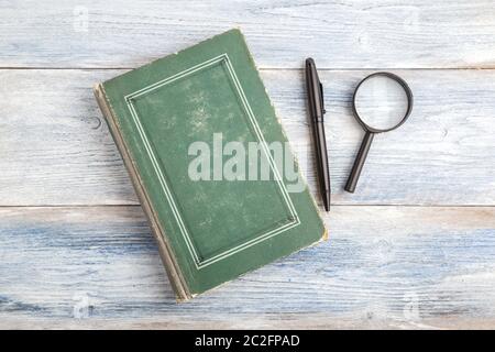 magnifying glass, pen and book on light blue old wooden background. top view. flat lay Stock Photo