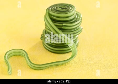 sweet treats, close up of green fruit gum snails on yellow background Stock Photo