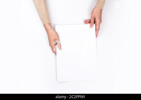 Woman's hands with perfect manicure holding  notepad as mockup for your design. White background, flat lay Stock Photo