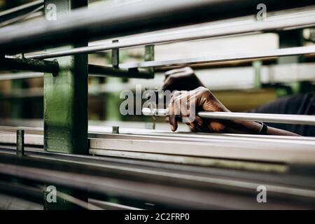 Close up of male hands measuring metallic pipe that lying on shelves in warehouse. Raw details and working process. Concept of engineering and product Stock Photo