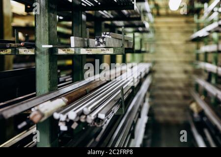 Close up of aluminum pipes in different shapes and forms lying on shelves in industrial factory. Concept of raw stuff and metallic material. Stock Photo