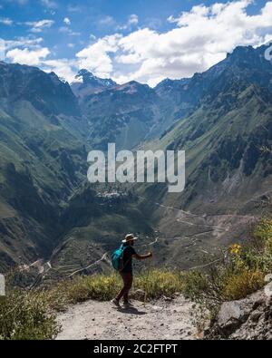young man is walking in a canyon, big mountains, clouds and blue sky Stock Photo