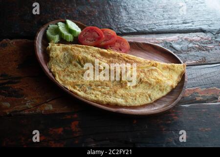 Top view of plain egg omelette with tomato and cucumber isolated on wooden background Stock Photo