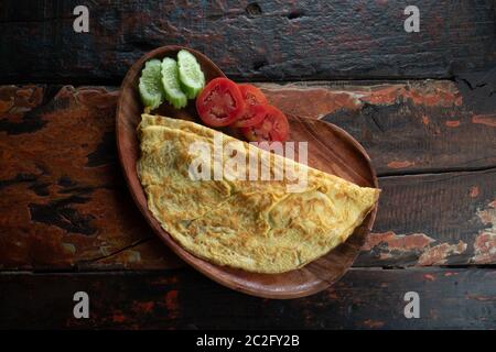 Top view of plain egg omelette with tomato and cucumber isolated on wooden background Stock Photo