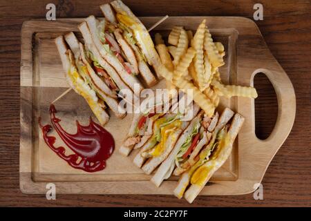 Top view of chicken club sandwiches and french fries isolated on wooden table Stock Photo
