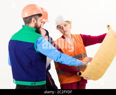 Misunderstanding concept. Men and woman in helmets, architects on busy faces looks at drawing, plan, blueprint, project, white background. Team of builder, engineer, architect arguing about project. Stock Photo