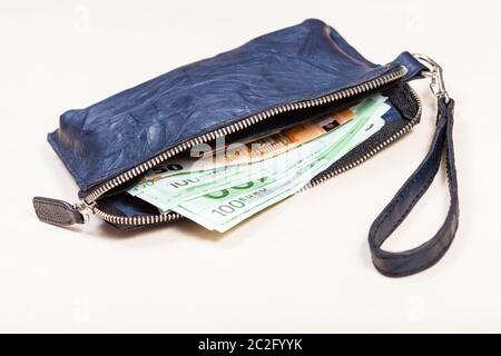 open blue leather wristlet purse bag with credit cards and euro banknotes on pale brown table Stock Photo