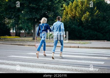 Back view of young happy couple running crosswalk in the street Stock Photo