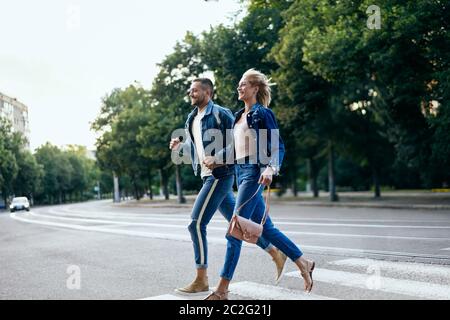 Young happy couple running crosswalk in the street Stock Photo