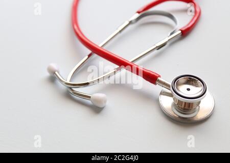 Red stethoscope on a grey background.This is an acoustic medical device for auscultation, or listening to the internal sounds of an animal or human Stock Photo