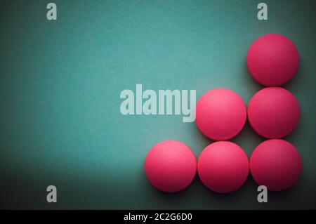 Pink pills laid out on a green background Stock Photo