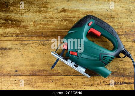 A jigsaw power tool on vintage wooden background with copy space for text. Stock Photo