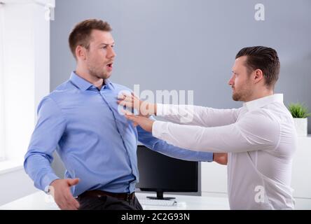 Two Angry Young Businessmen Quarreling With Each Other Fighting In The Office Stock Photo
