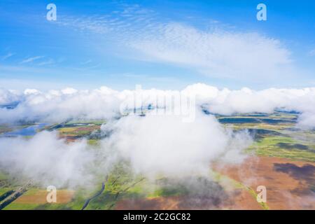Flying through the fluffy clouds layers. Camera above ground. Amazing soft white clouds moving slowly on the clear sky. Stock Photo