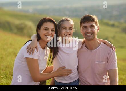Smiling family hugs on the background of nature in summer. Stock Photo