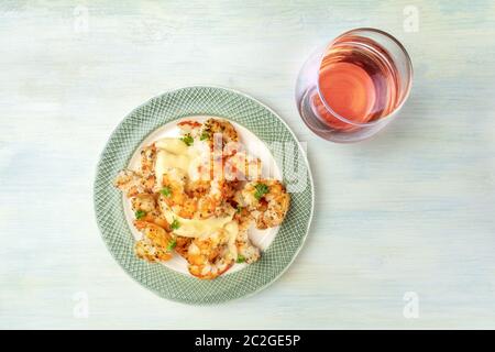 Fired shrimps with fresh parsley leaves, with a dressing, a glass of rose wine, and a place for text Stock Photo
