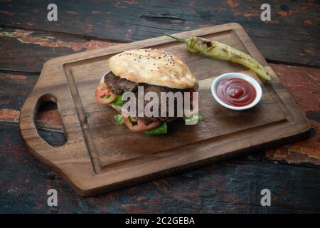 Turkish Kofte Ekmek. Meatball Sandwich with tomatoes, onion and green pepper isolated on rustic wooden background Stock Photo