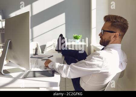 Businessman resting relaxes meditating dreams at the workplace at the table with a computer in office Stock Photo